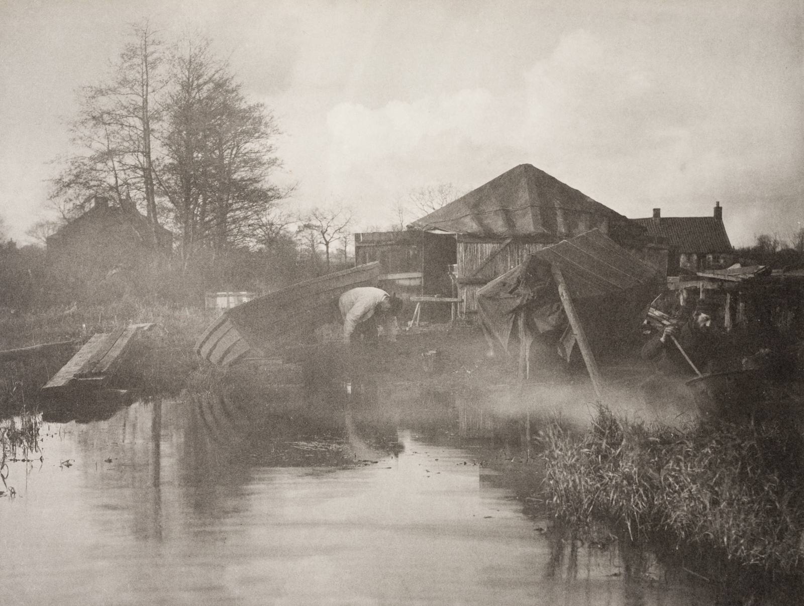 Platinum print of boat-builders at work: hauled-up hulls, sheds, and still water reflections on the Norfolk Broads.
